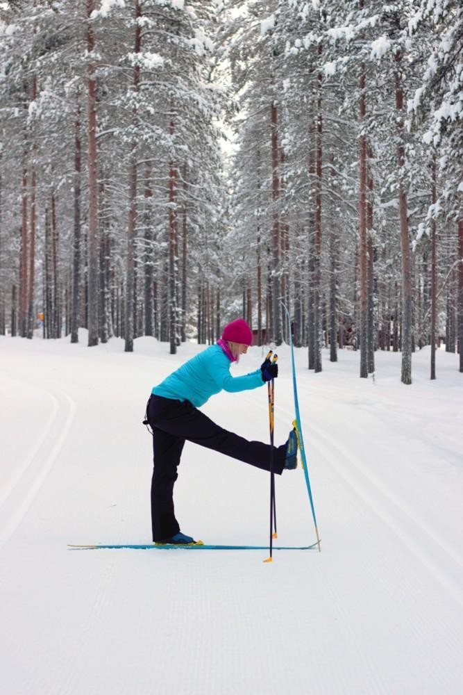 Nainen suksilla. Etummainen jalka on ojennettu eteen niin, että etummaisen jalan suksi on pystyssä maassa.